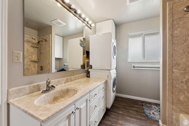 full bathroom with stacked washer / dryer, baseboards, a shower, wood finished floors, and vanity
