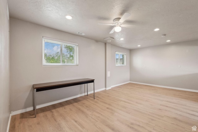 below grade area with light wood-style flooring, a textured ceiling, recessed lighting, baseboards, and ceiling fan