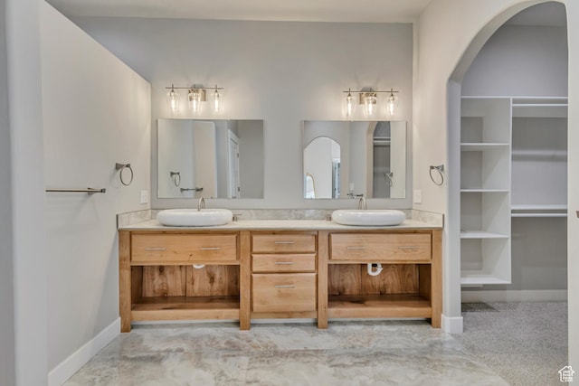 full bathroom featuring double vanity, a spacious closet, and baseboards