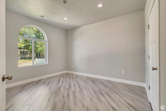 spare room featuring a textured ceiling, light wood-style floors, recessed lighting, and baseboards
