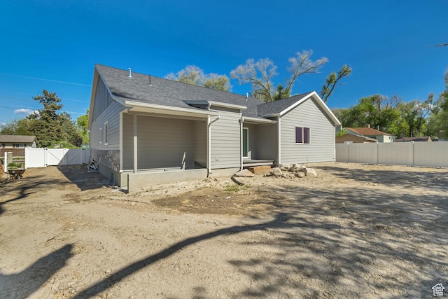 rear view of property with fence, a gate, and roof with shingles