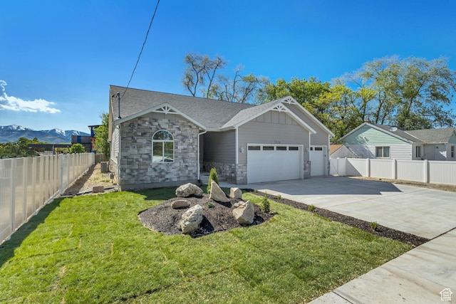 view of front of home featuring concrete driveway, an attached garage, stone siding, and a mountain view