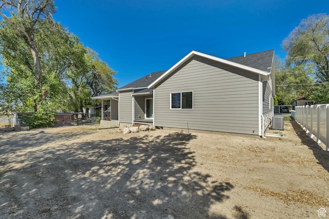 rear view of house featuring fence, roof with shingles, and cooling unit