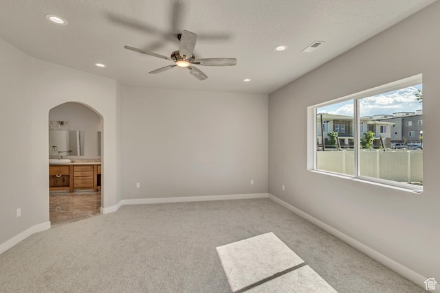 empty room featuring arched walkways, light carpet, recessed lighting, ceiling fan, and baseboards
