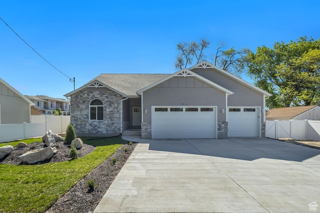 view of front of property with stone siding, an attached garage, fence, and driveway