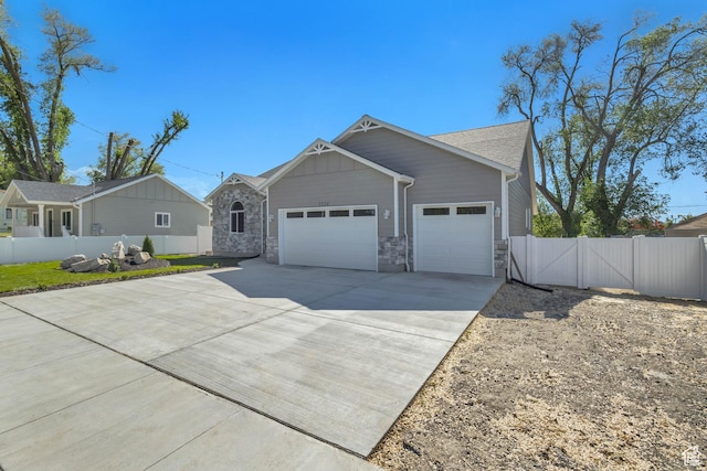 view of front of property with an attached garage, fence, concrete driveway, a gate, and stone siding