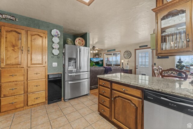 6407 N Dry Fork Cyn W, Dry Fork, UT 84078 - kitchen featuring stainless steel appliances, plenty of natural light, light tile patterned flooring, brown cabinetry, and a textured ceiling