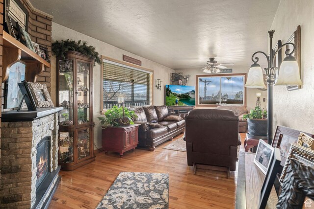 6407 N Dry Fork Cyn W, Dry Fork, UT 84078 - living area featuring a ceiling fan, a stone fireplace, light wood-style flooring, and a textured ceiling