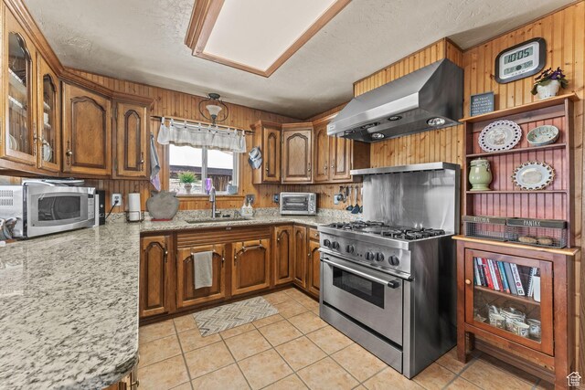 6407 N Dry Fork Cyn W, Dry Fork, UT 84078 - kitchen featuring range hood, appliances with stainless steel finishes, brown cabinets, a sink, and wood walls