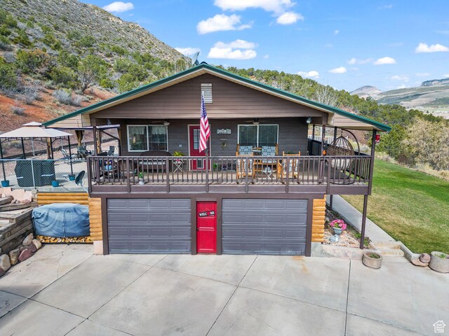 6407 N Dry Fork Cyn W, Dry Fork, UT 84078 - view of front of home featuring an attached garage, a mountain view, concrete driveway, a ceiling fan, and a front yard