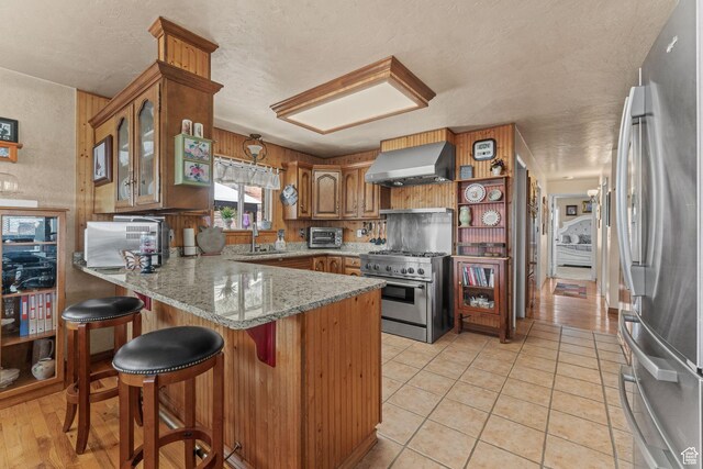 6407 N Dry Fork Cyn W, Dry Fork, UT 84078 - kitchen featuring appliances with stainless steel finishes, ventilation hood, a peninsula, a sink, and brown cabinetry