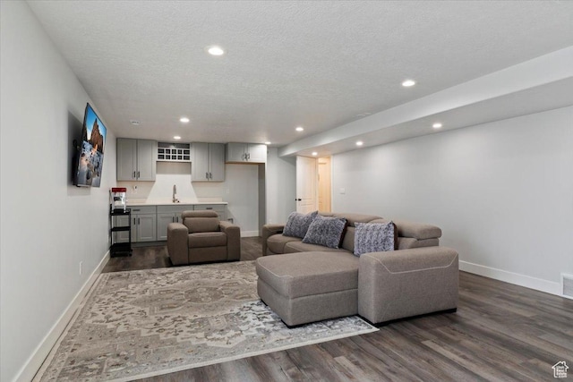 5118 N Blackbrush Dr, Eagle Mountain, UT 84005 - living room with baseboards, dark wood-type flooring, a textured ceiling, recessed lighting, and bar with sink