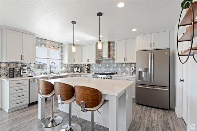 5118 N Blackbrush Dr, Eagle Mountain, UT 84005 - kitchen with stainless steel appliances, wall chimney range hood, light wood-style flooring, decorative backsplash, and recessed lighting