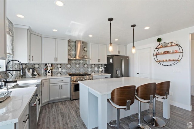 5118 N Blackbrush Dr, Eagle Mountain, UT 84005 - kitchen with appliances with stainless steel finishes, wall chimney range hood, dark wood-style flooring, tasteful backsplash, and recessed lighting