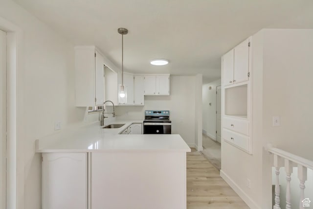 kitchen with stainless steel electric stove, a sink, a peninsula, light wood finished floors, and light countertops