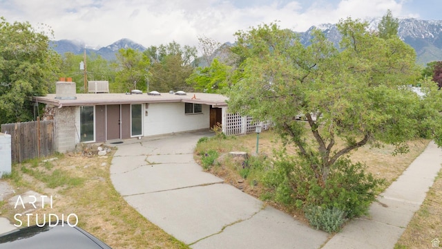 941 E Carnation Dr, Sandy, UT 84094 - view of front facade featuring fence, a mountain view, and a chimney