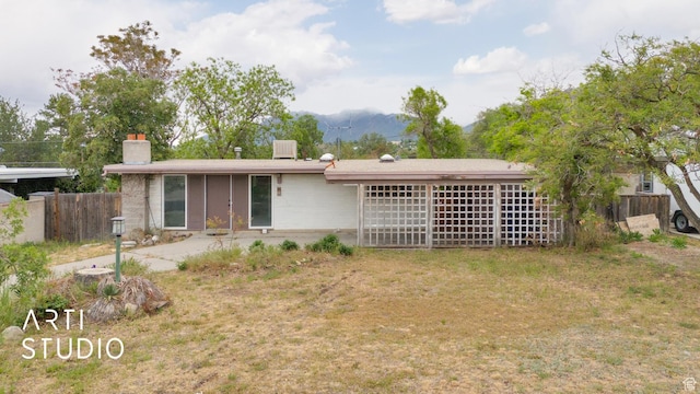 941 E Carnation Dr, Sandy, UT 84094 - rear view of house featuring fence, a chimney, a mountain view, and a patio