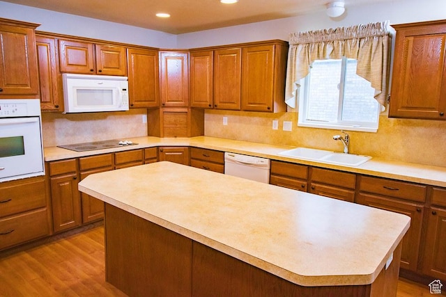 kitchen featuring white appliances, a sink, light countertops, decorative backsplash, and a center island