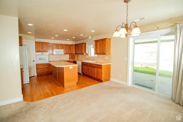 kitchen with white appliances, a sink, brown cabinets, recessed lighting, and light colored carpet