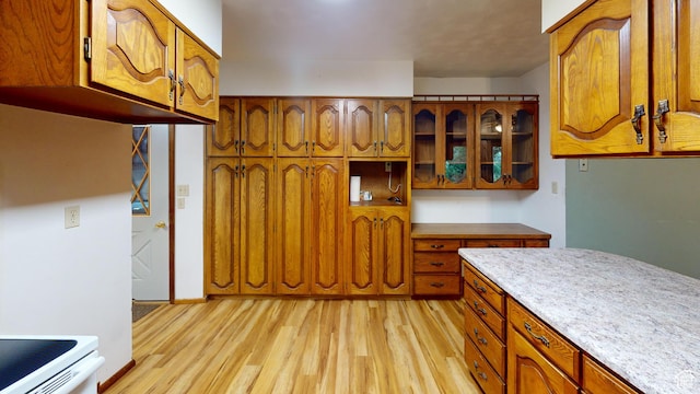 662 N 1600 E, Preston, ID 83263 - kitchen with light wood finished floors, brown cabinetry, and glass insert cabinets