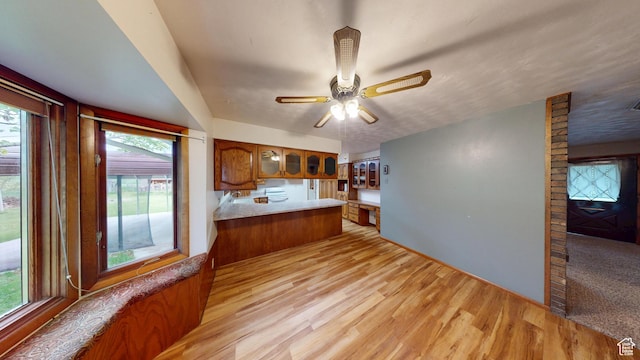 662 N 1600 E, Preston, ID 83263 - kitchen with brown cabinets, glass insert cabinets, light wood finished floors, a peninsula, and ceiling fan