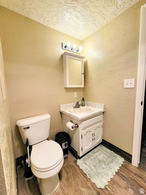 273 S 700 W, Parowan, UT 84761 - half bathroom featuring wood finished floors, toilet, a textured ceiling, vanity, and a textured wall
