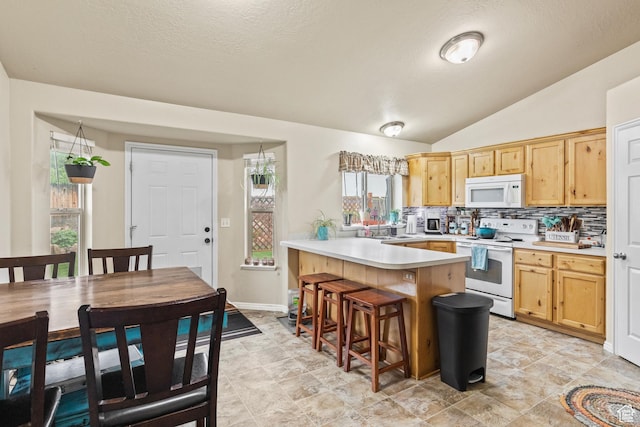 78 N Peach St E, Santaquin, UT 84655 - kitchen featuring white appliances, a peninsula, light countertops, backsplash, and a breakfast bar area