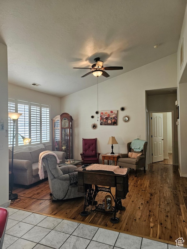 living room with tile patterned flooring, ceiling fan, and vaulted ceiling