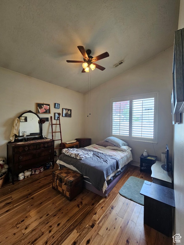 bedroom featuring vaulted ceiling, wood-type flooring, a textured ceiling, and a ceiling fan