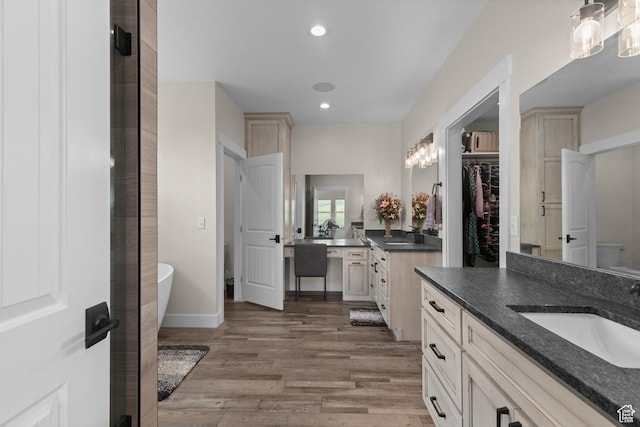 22 Old Ranch Rd, Montpelier, ID 83254 - bathroom featuring two vanities, wood finished floors, a freestanding tub, recessed lighting, and a walk in closet