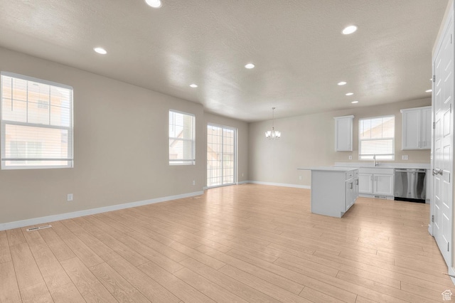 kitchen with dishwasher, a chandelier, open floor plan, light wood-style floors, and light countertops