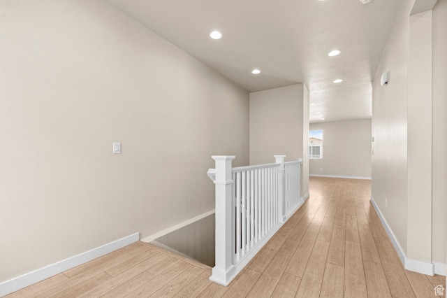 hallway with an upstairs landing, recessed lighting, wood-type flooring, and baseboards