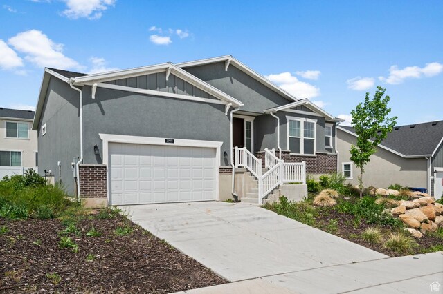 ranch-style house featuring brick siding, a garage, driveway, board and batten siding, and stucco siding