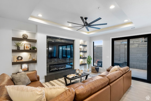 5266 W 2480 S Unit 132, Hurricane, UT 84737 - living room featuring a tile fireplace, a tray ceiling, ceiling fan, recessed lighting, and light wood-style floors