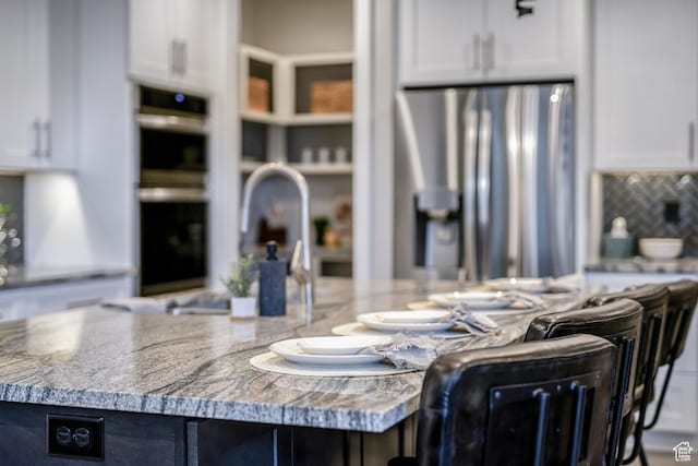 5266 W 2480 S Unit 132, Hurricane, UT 84737 - kitchen with stainless steel fridge with ice dispenser, white cabinetry, a kitchen island, and tasteful backsplash