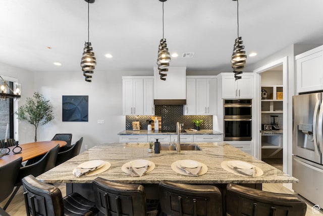5266 W 2480 S Unit 132, Hurricane, UT 84737 - kitchen with stainless steel appliances, a sink, backsplash, light stone countertops, and a breakfast bar area