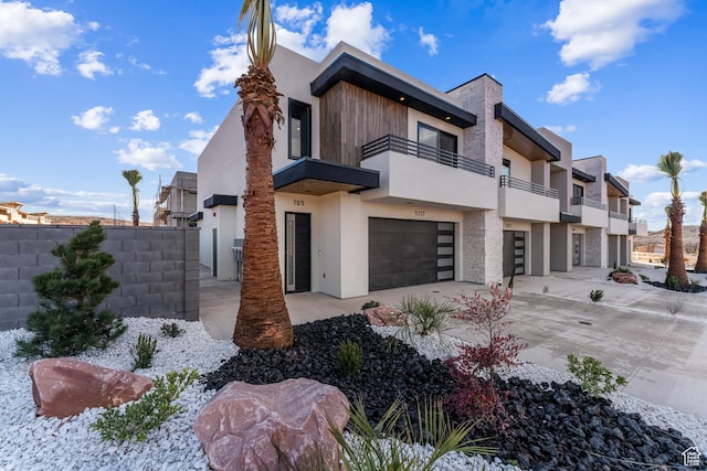 5266 W 2480 S Unit 132, Hurricane, UT 84737 - view of front of house featuring a balcony, an attached garage, fence, driveway, and stucco siding