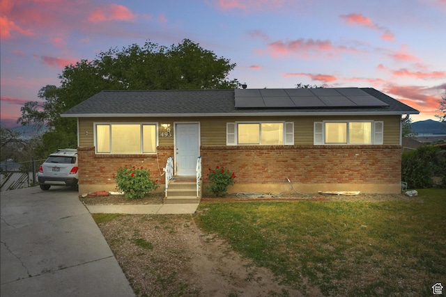 493 N 1025 W St W, Orem, UT 84057 - view of front of house featuring brick siding, roof mounted solar panels, a front yard, concrete driveway, and roof with shingles