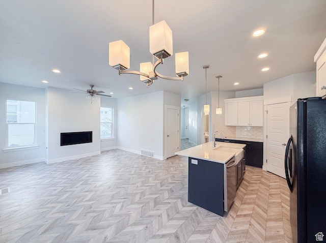 5107 W Harlow Way, Herriman, UT 84096 - kitchen featuring freestanding refrigerator, ceiling fan, light countertops, a kitchen island with sink, and decorative backsplash