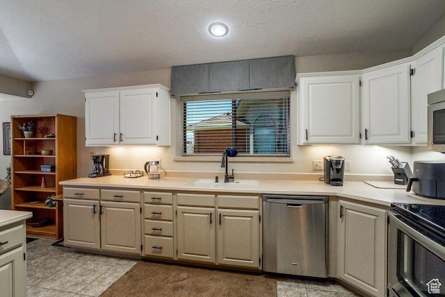 kitchen with appliances with stainless steel finishes, a sink, light countertops, a textured ceiling, and white cabinetry