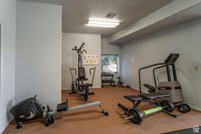 exercise area featuring carpet floors, a textured ceiling, and baseboards