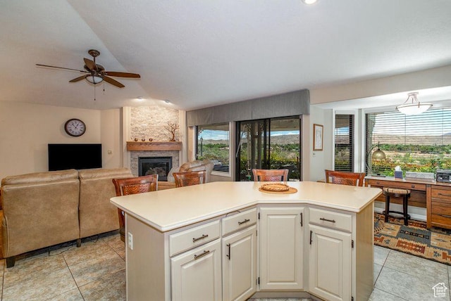 kitchen with ceiling fan, light countertops, a fireplace, and light tile patterned flooring