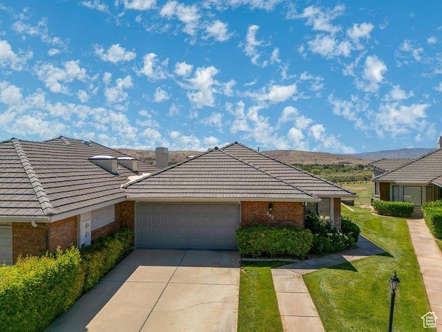 view of front of home featuring brick siding, a tile roof, a garage, driveway, and a front yard