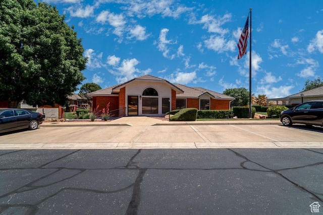 ranch-style house featuring uncovered parking and a tile roof