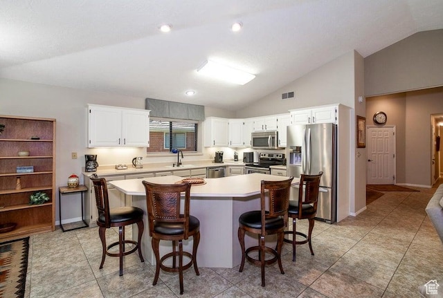 kitchen with stainless steel appliances, lofted ceiling, a sink, light countertops, and a center island