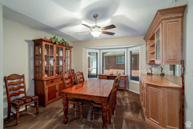 dining space featuring dark colored carpet, a ceiling fan, and baseboards
