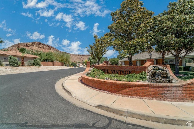 view of asphalt road featuring a mountain view, sidewalks, and curbs
