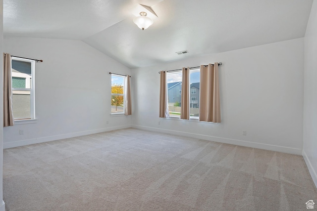 carpeted spare room with vaulted ceiling, plenty of natural light, and baseboards