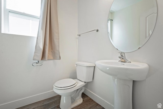 bathroom with baseboards, toilet, wood finished floors, and a sink