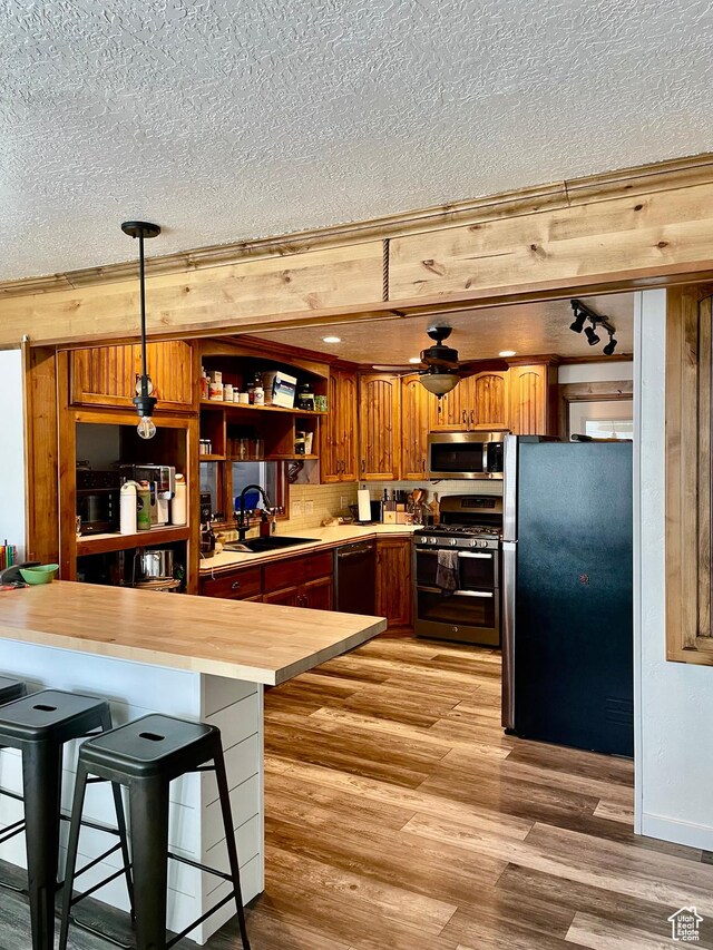 229 N 300 W, Salina, UT 84654 - kitchen with stainless steel appliances, a sink, butcher block countertops, a textured ceiling, and light wood-style floors